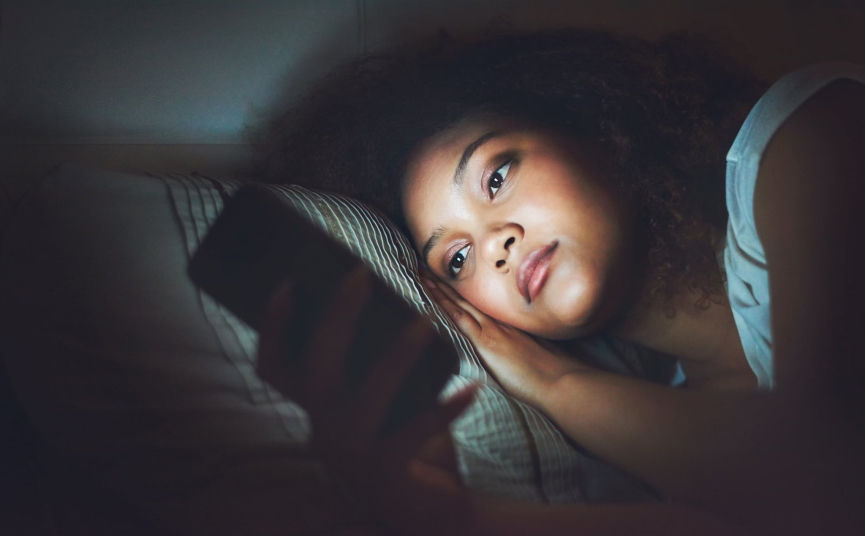 woman scrolling on phone in bed at night