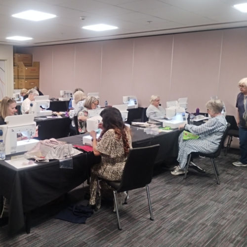 A group of women sat at sewing machines at a creative workshop learning a new textile art technique