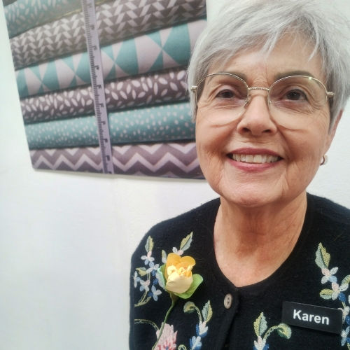 A smiling woman pleased with the creative rose she has made and is wearing