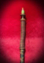 Handcrafted decorative staff with intricate wrapping, green brass tip on red.