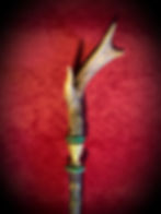 Handmade antler-top staff, wood, brass, green accents, red background.