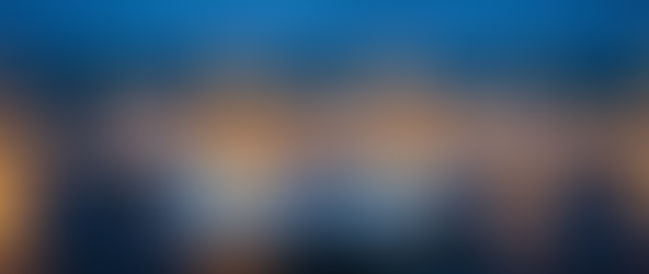 A high-angle view of a busy aerospace delivery center at twilight, crowded with multiple unbranded, plain white Airbus A320neo and A321neo aircraft. Ground crews and support vehicles surround the jets under bright floodlights, while one white aircraft taxies for departure in the foreground against a deep blue evening sky.