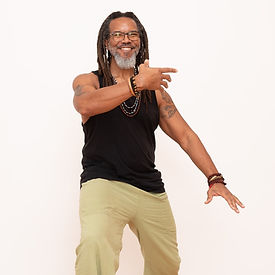 Jordan in natural green pants and black tank, flowing into a balanced Tai Chi stance, grounding his energy and balancing Qi.