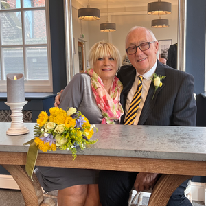 a bride and groom sit at a table with flowers on it