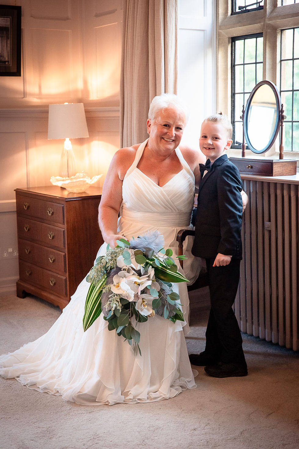 a woman in a wedding dress stands next to a boy in a tuxedo