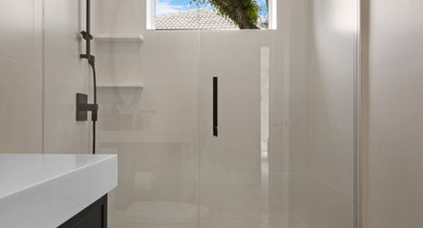 Modern bathroom with glass shower door, white toilet, and patterned tile flooring.