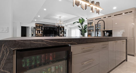 Modern kitchen with a dark countertop and cabinets, also a beverage cooler.