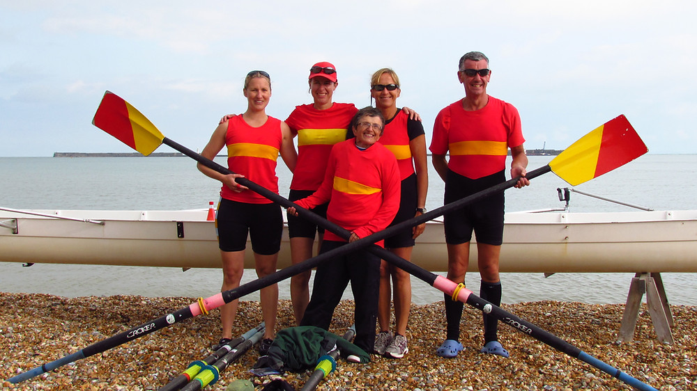 Team of 5 rowers standing in front of their boat