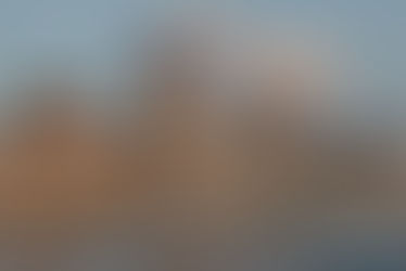 The Hungarian Parliament building from outside with 2 boats on the Danube and a few clouds.