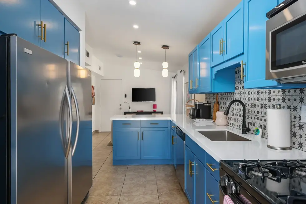 Modern kitchen with blue cabinetry, white countertops, and stainless steel appliances in The Bowie Suite