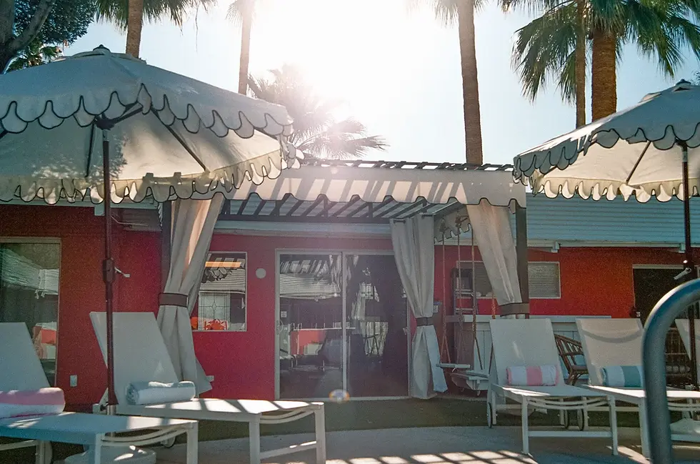 Retro poolside cabana with red walls and teal awnings at Palm Springs vacation rental