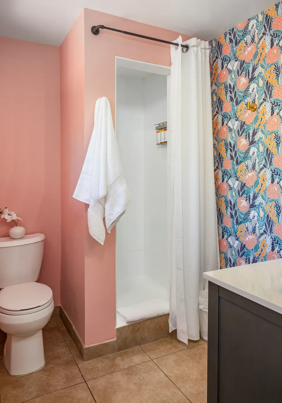 Modern bathroom with pink walls, floral wallpaper, walk-in shower, and dark vanity in Palm Springs downtown property