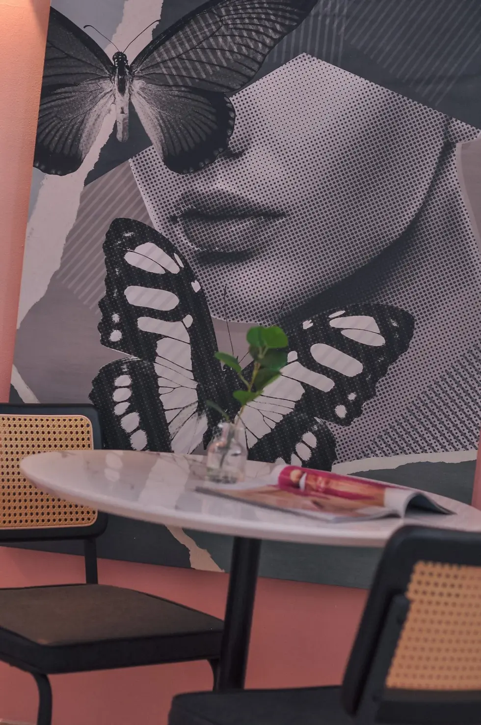 Pop art butterfly artwork and halftone portrait in modern Palm Springs boutique hotel living room with rattan furniture and