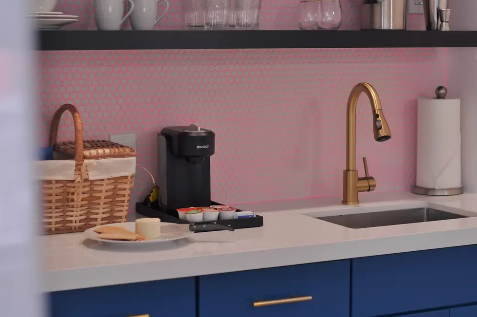 Modern kitchenette with pink geometric backsplash, navy cabinetry, and brass faucet in Palm Springs property