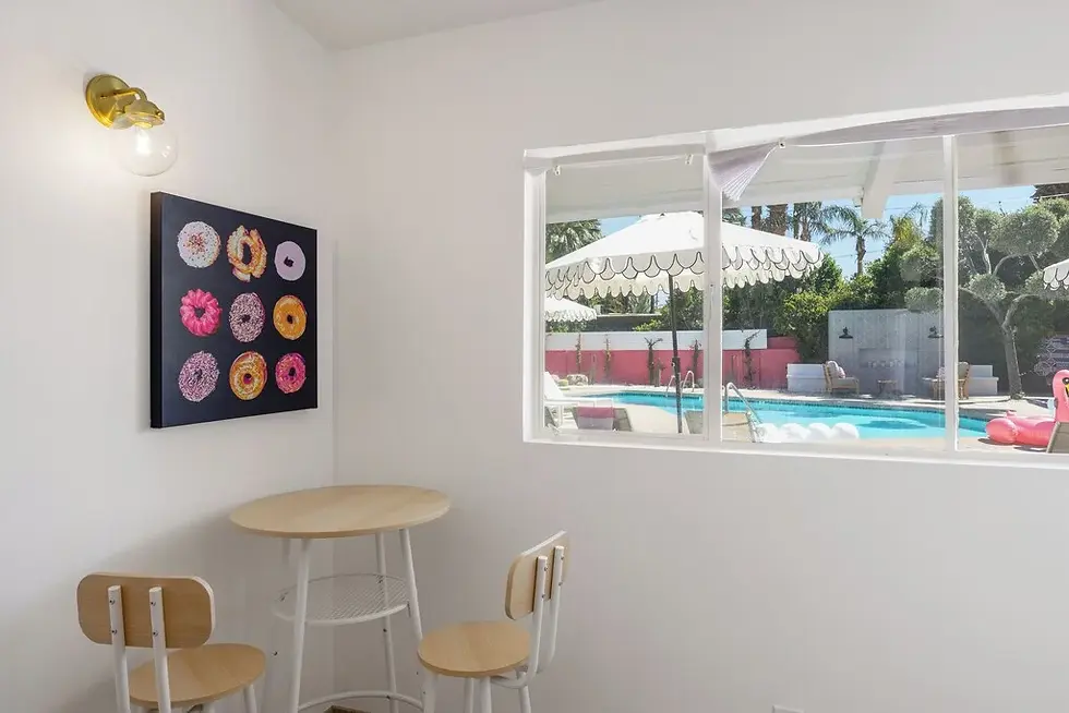 Modern dining area with round table overlooking resort pool, contemporary art, brass lighting in Palm Springs