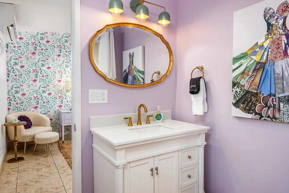 Luxury bathroom with lavender walls, gold-framed mirror, and fashion-inspired decor at Palm Springs boutique suite