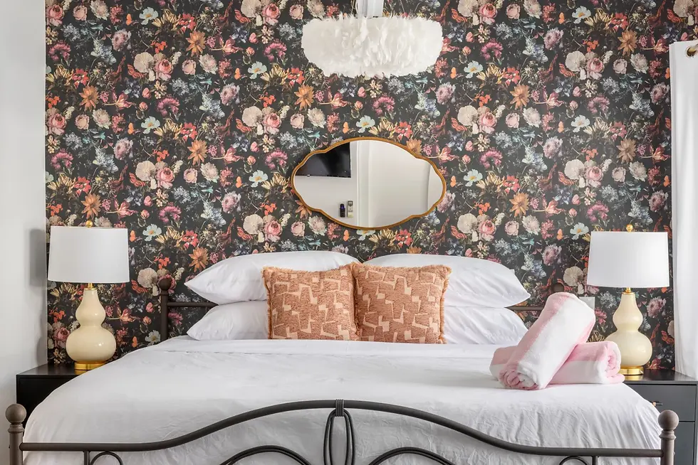 Adults only resort boutique suite bedroom with bold floral wallpaper accent wall, gold mirror, and mid-century modern design