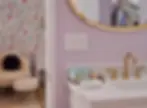 Luxury bathroom with lavender walls, gold fixtures, and elegant vanity in The Brigitte Suite, Palm Springs