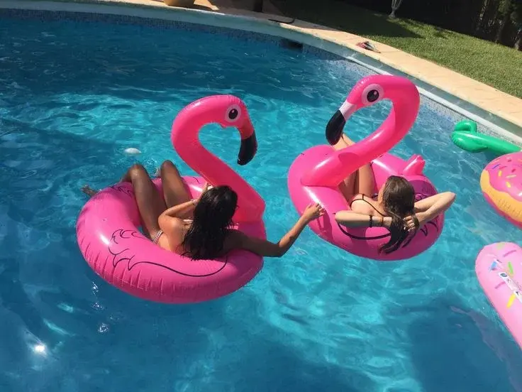 Guests relax on pink flamingo floats in the turquoise pool at a Palm Springs boutique hotel with lush landscaping
