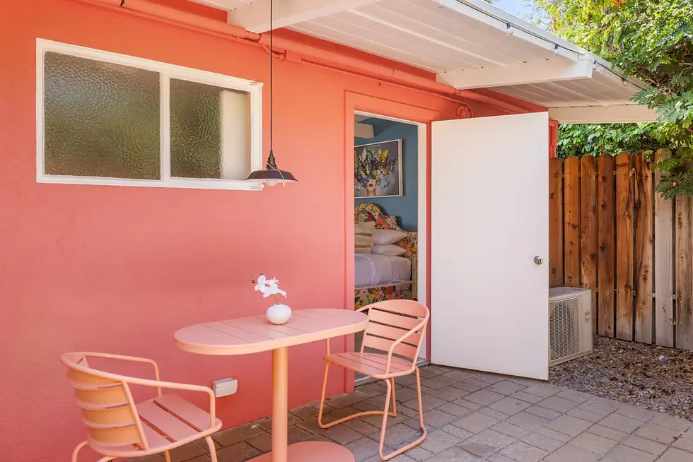 Coral pink mid-century modern patio with dining table at pet friendly vacation rental in Palm Springs with mountain views