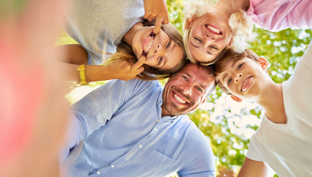 Glückliche Familie macht Grimassen im Park, sonniger Tag, alle lächeln.