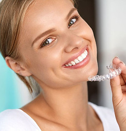 Lächelnde Frau hält eine transparente Zahnschiene zur Zahnkorrektur