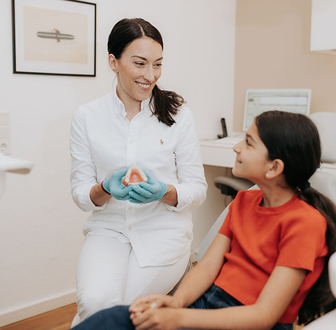 Dr Alexandra Hofmayer zeigt einer jungen Patientin ein Gebiss