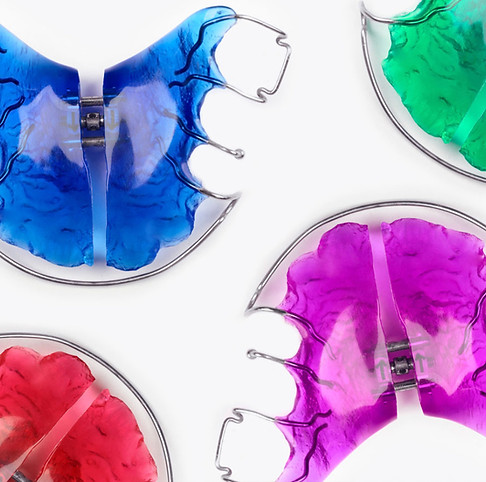 Vier farbige lose Zahnspangen in Nahaufnahme der kieferorthopädischen Geräte als Lückenhalter bei Milchzähnen