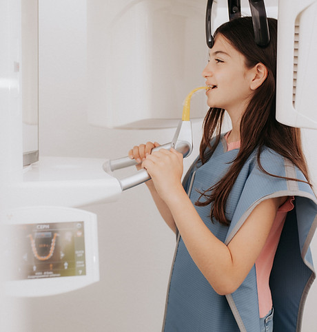 Teenager steht in Zahnarztpraxis, Zahnröntgen wird erstellt