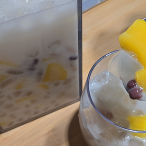 A vibrant, overflowing glass of Mango Halo Halo Sago with glistening mango chunks, with a splash of milky goodness. With close-up of the Dole Mango Chunks 