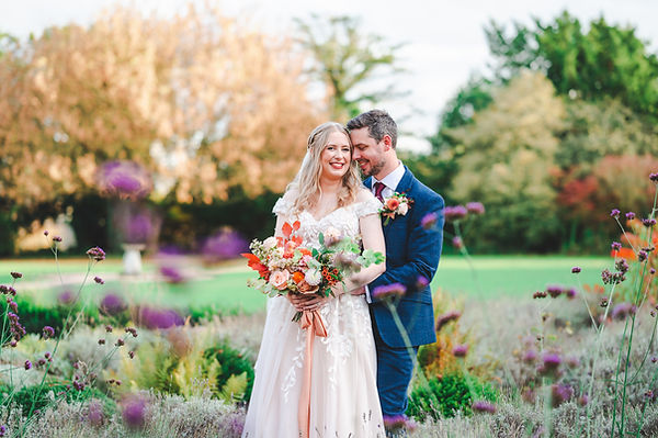 A bride and groom enjoying a quiet moment to themselves in the autumnal gardens of caswell house, brize norton, oxfordshire