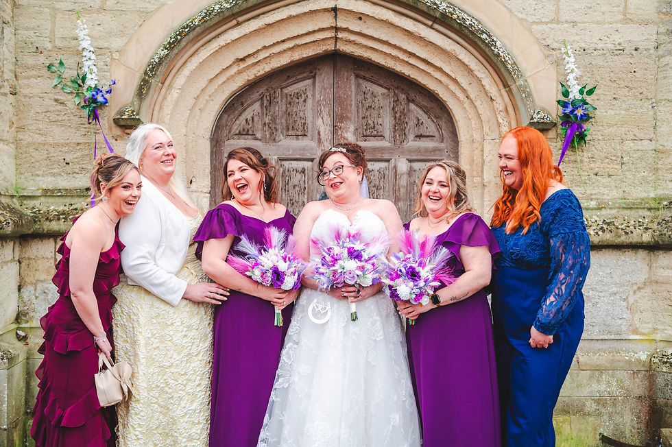 Group of people in purple dresses and white wedding dress smiling during group photos at church