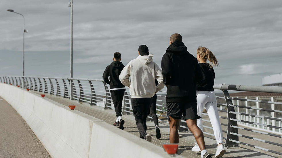 A diverse group of adults jogging together on a city bridge during the day.