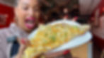 tamika holding mac and cheese pizza with mouth open