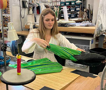 Nyta working on a green and black garment during her apprenticeship through The ReThread Project