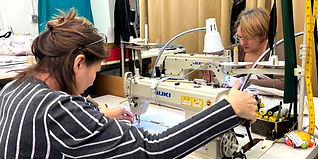 Two garment makers hard at work at their sewing machines.