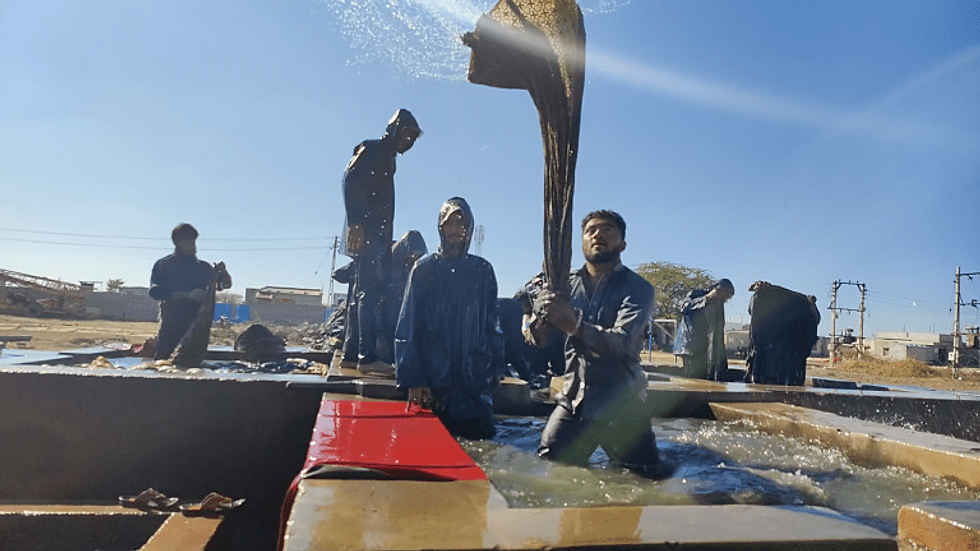 A person washing clothes using time-honored methods.