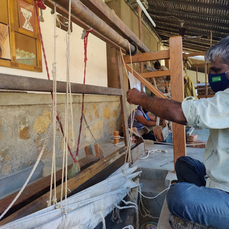 Skilled weaver crafting a blanket in a rural setting.