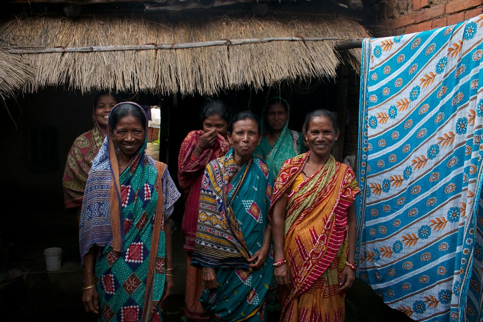 Confidently smiling, rural women entrepreneurs stand together inside a hut, showcasing their strength and determination.