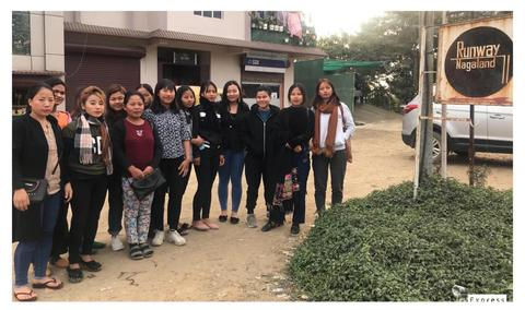The team of Runway Nagaland standing together beside its signpost.
