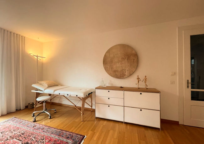Heller Hypnotherapie-Praxisraum in Bern mit Behandlungsliege und rundem Wandbild.