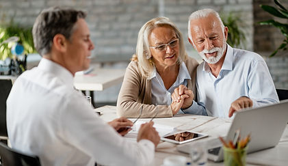 happy-senior-couple-holding-hands-using-laptop-while-having-meeting-with-financial-advisor