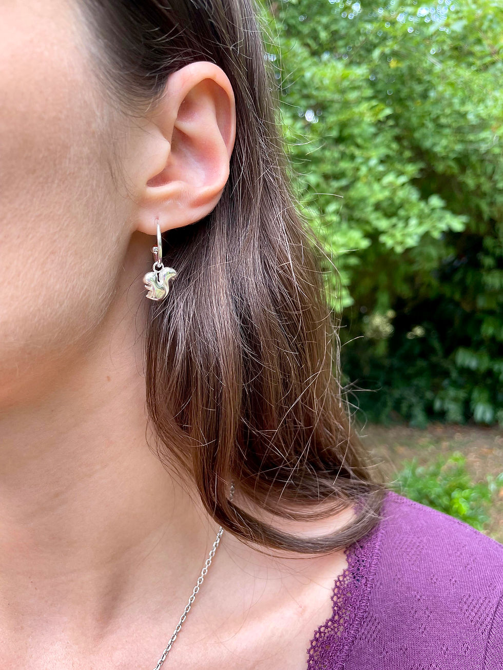 Paire de créoles en argent avec pendentif au motif d'un écureuil vue de portée.