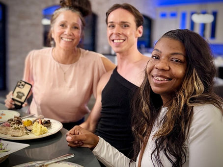 Three people smiling at a dinner table during the AcademySTAY Third Anniversary celebration.