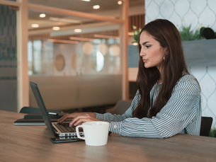 Small business owner reviewing recurring costs and cost reduction strategies at a laptop