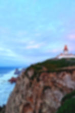 Lighthouse on the cliffs of Cabo da Roca, Portugal, overlooking the Atlantic Ocean under a soft blue sky