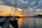 Sailboats in Riga harbor at sunset with warm sky and reflections on water