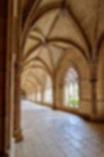 Gothic vaulted corridor inside Batalha Monastery with soft light and repeating arches