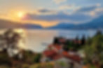 Sunset over the Bay of Kotor in Montenegro with red rooftops, mountains, and calm sea