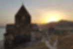 Sevanavank Monastery at sunset by Lake Sevan, Armenia, with ancient stone church and warm golden light over surrounding hills